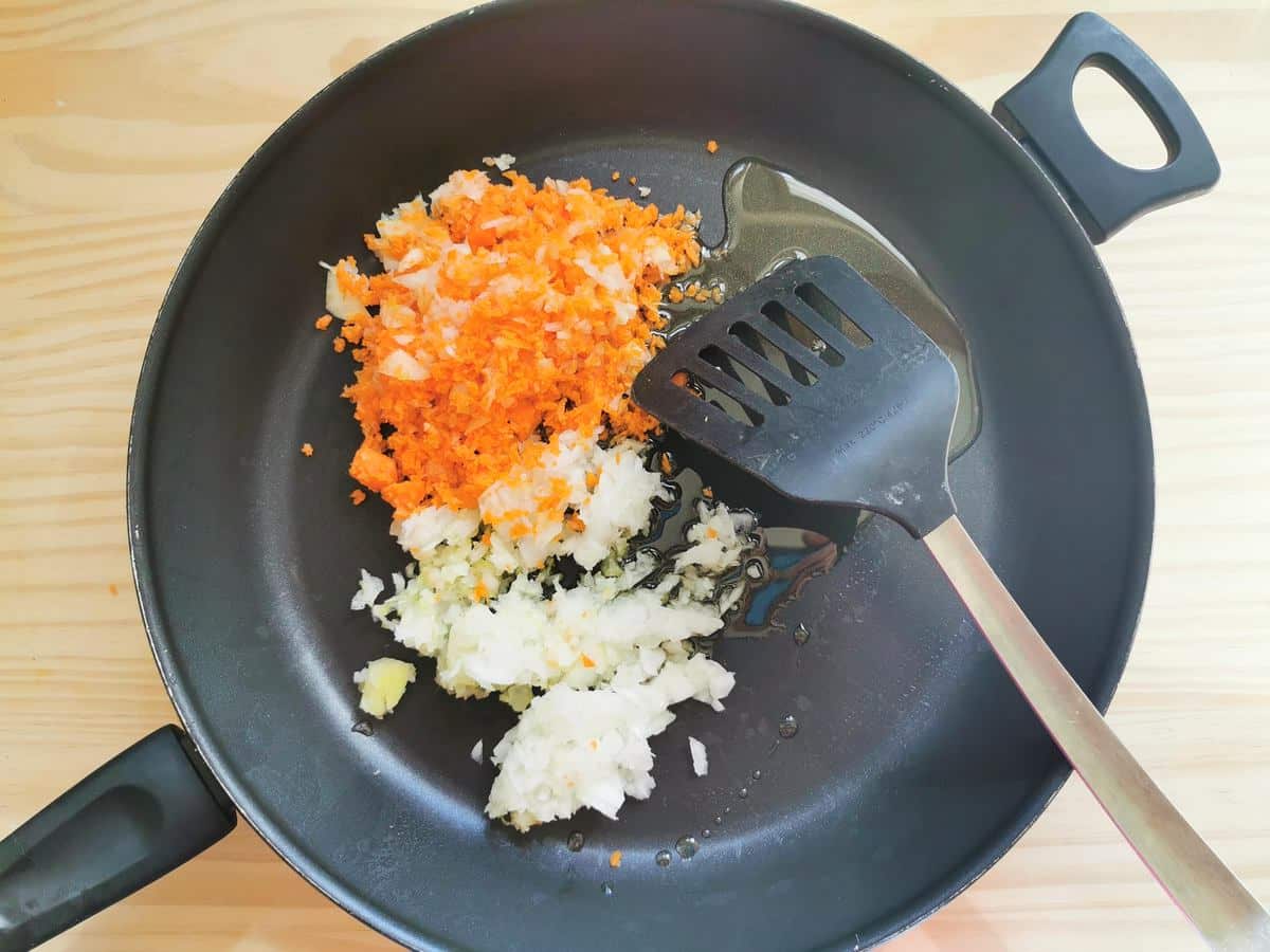 Finely chopped onion, celery and carrots cooking in skillet with olive oil.