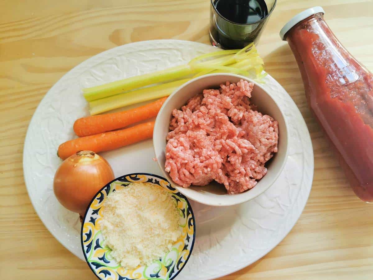 Ingredients for veal ragu plus a bowl of grated Parmigiano cheese.