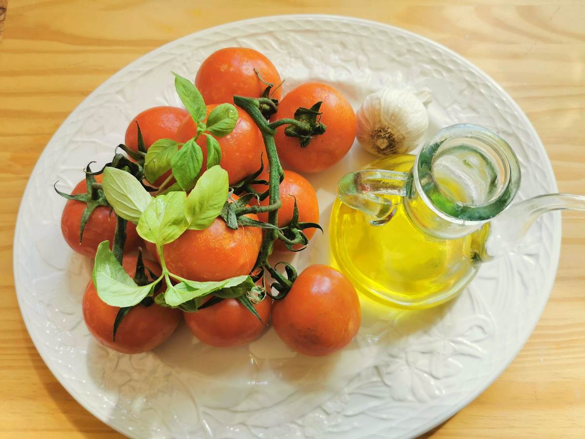 Ingredients for fresh tomato and garlic spaghetti on white plate.