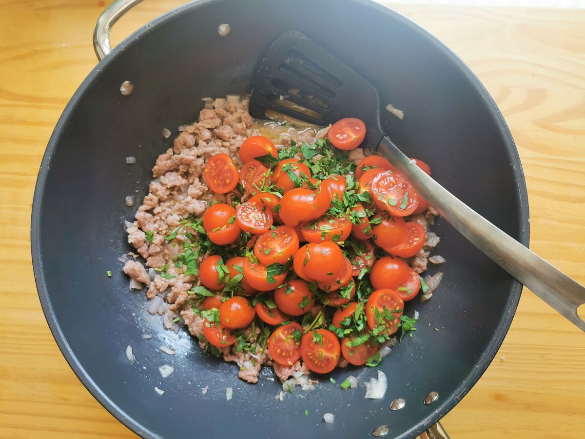 Halved cherry tomatoes and chopped parsley added to sausage and onion in large skillet.
