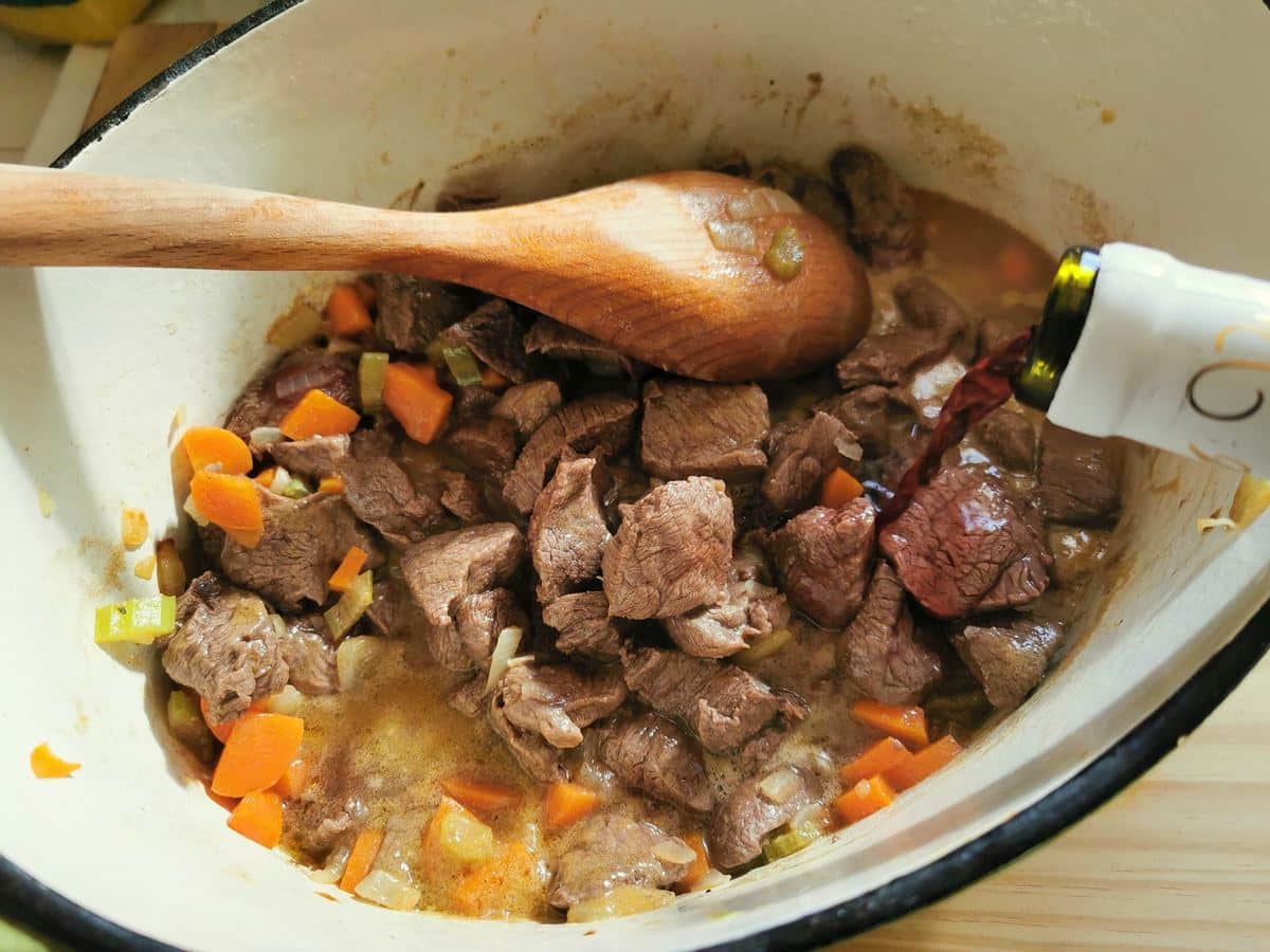 Adding red wine to the venison and vegetables.