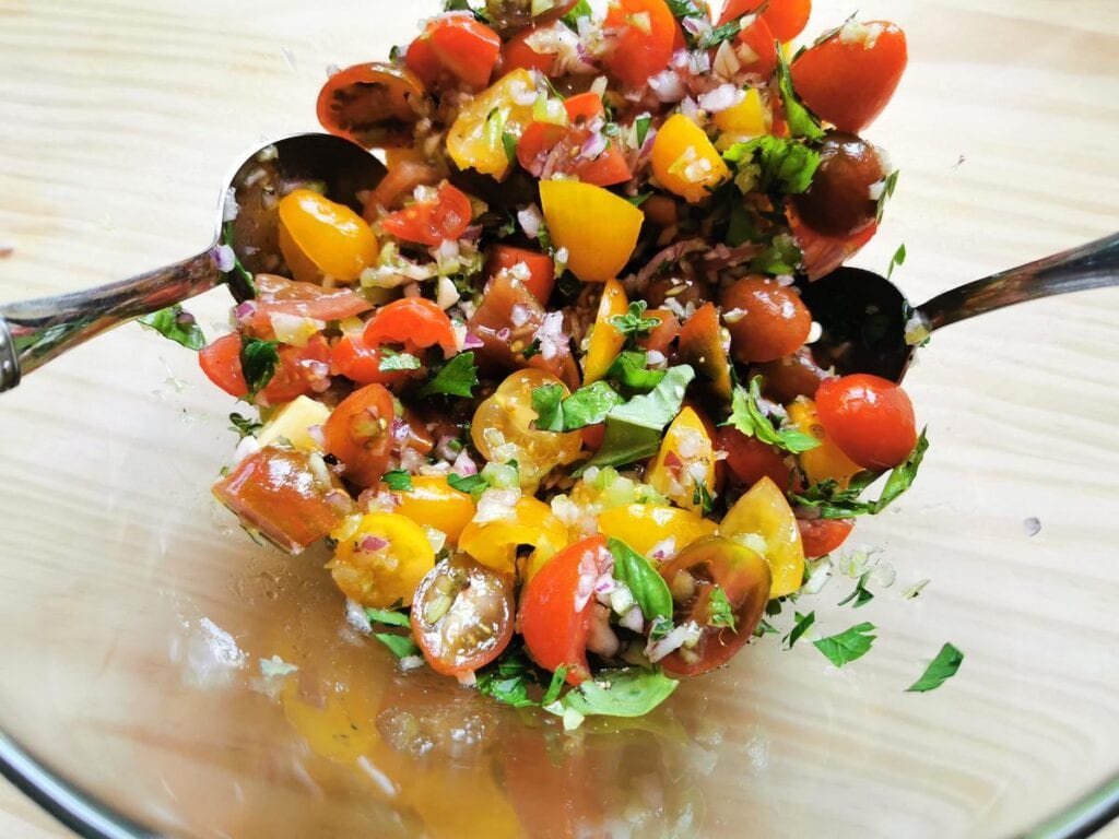 ingredients for positano condiment mixed together in glass bowl