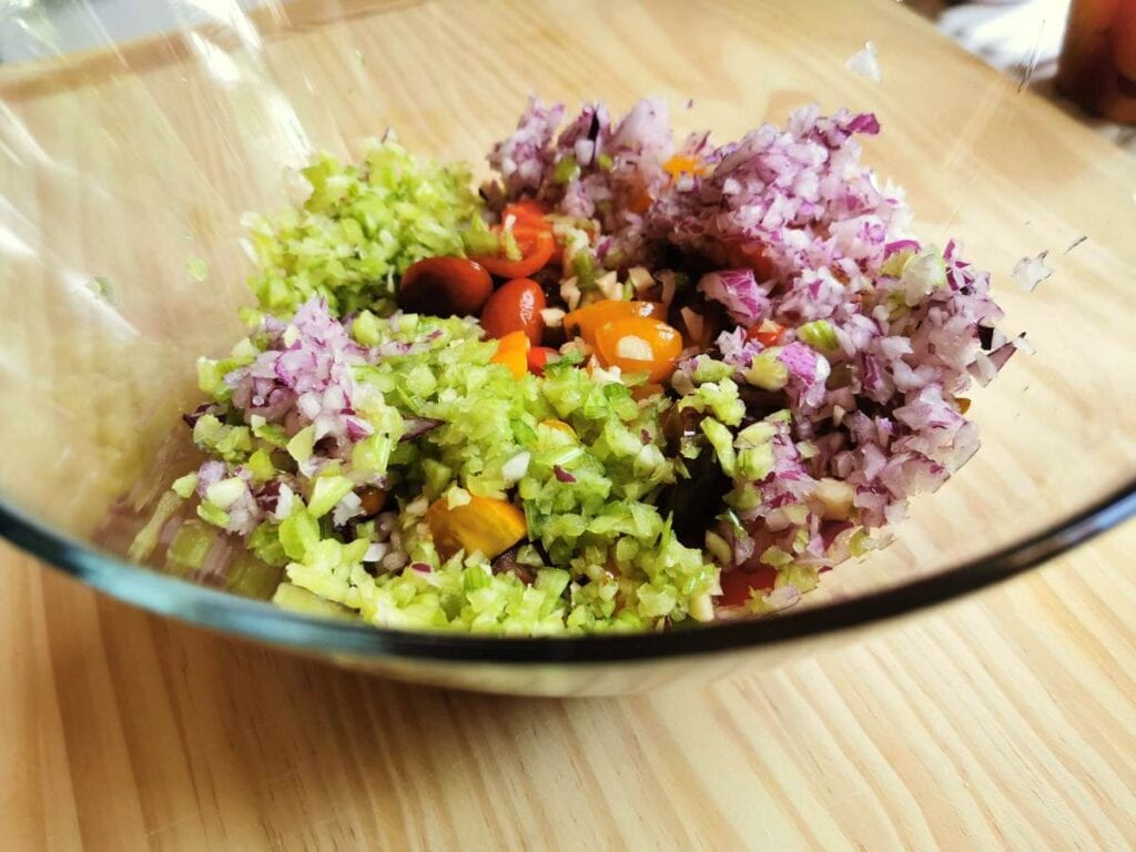 chopped vegetables and tomatoes in large glass bowl