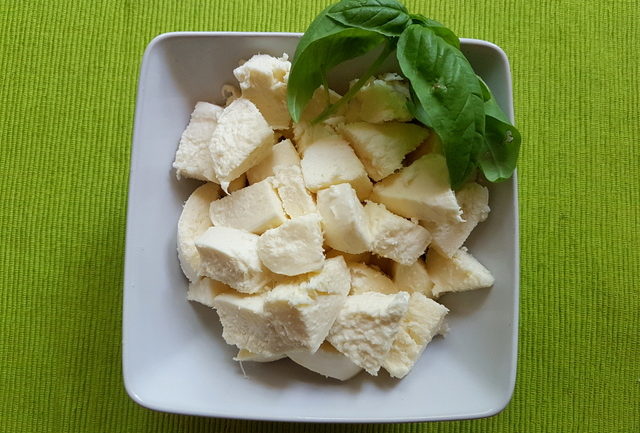 fresh mozzarella pieces in white bowl with basil