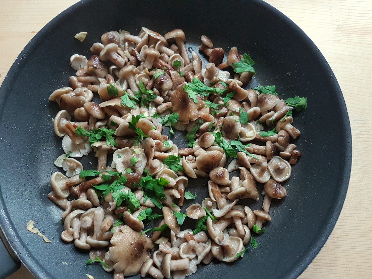 Wild mushrooms in a skillet with parsley.