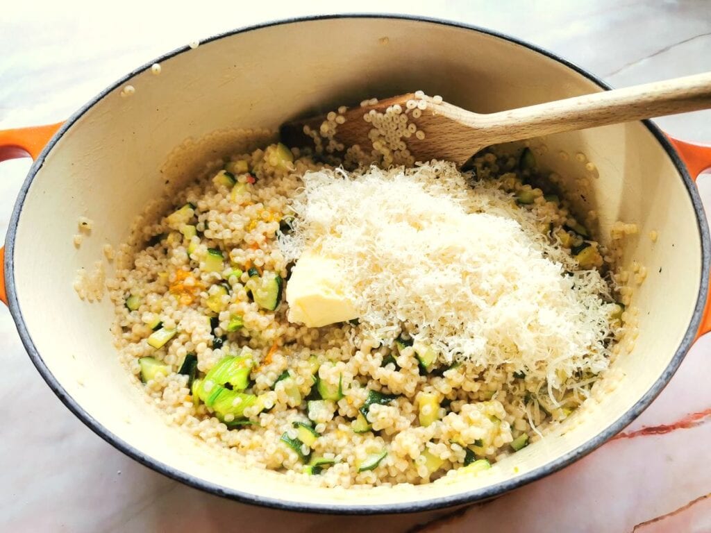 butter and grated parmigiano cheese in Dutch oven with zucchini flower pasta risotto.