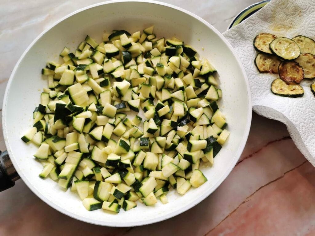 small cubes of zucchini in frying pan and fried rounds of zucchini on plate.