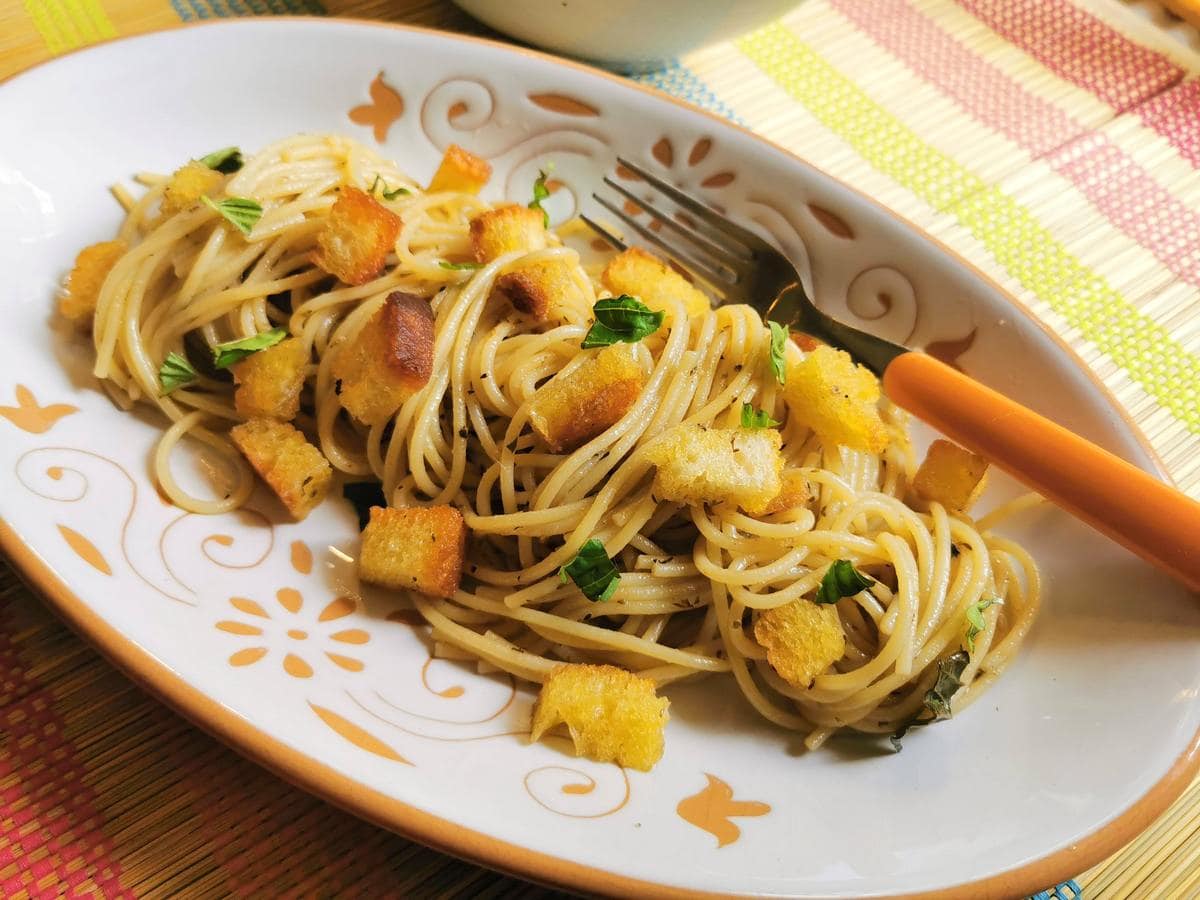 Anchovy pasta from Naples (spaghetti alla Gennaro) in oval white plate with fork.