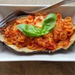 Eggplant boat garnished with basil in a dish.