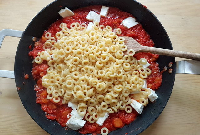 pasta added to tomato and eggplant sauce in frying pan