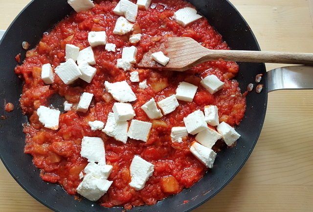 tomato and eggplant sauce with pieces of primo sale cheese in frying pan