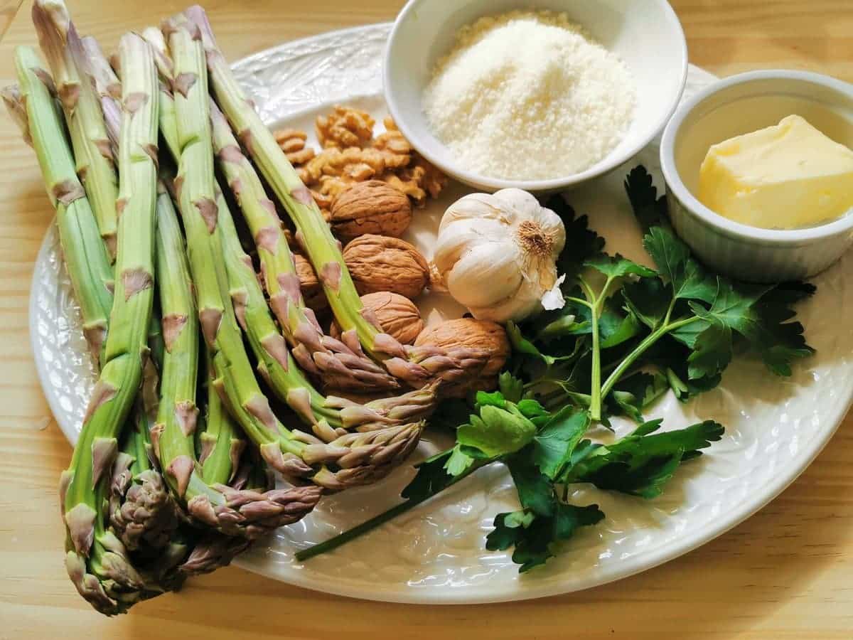 ingredients for asparagus and walnut pasta on white plate