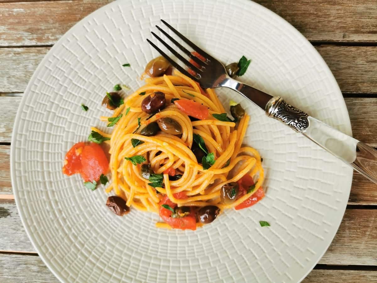 spaghetti alla puttanesca on a plate with a fork