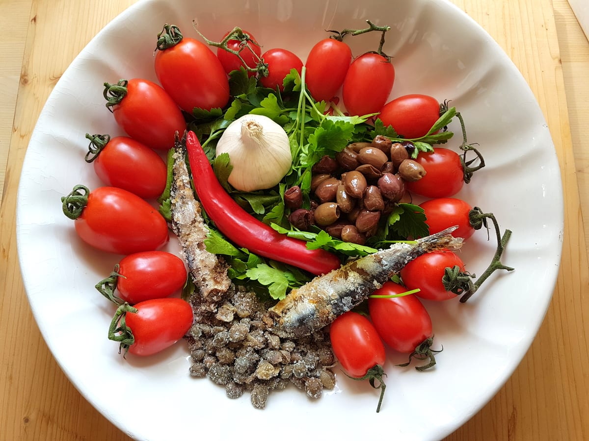 Ingredients for spaghetti alla puttanesca in white bowl.