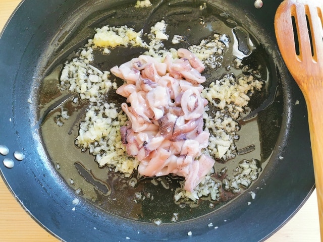 chopped calamari with onionsand garlic cooking in skillet