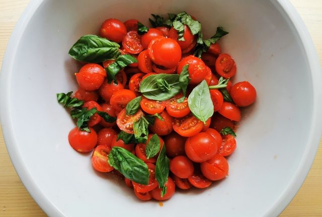 halved cherry tomatoes marinating in salt, olive oil and basil