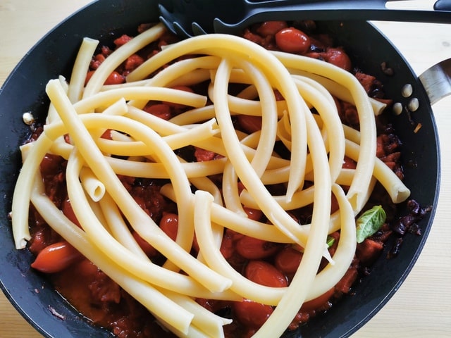 cooked ziti in skillet with spicy sausage and tomato sauce