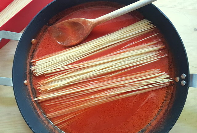 uncooked spaghetti in tomato sauce