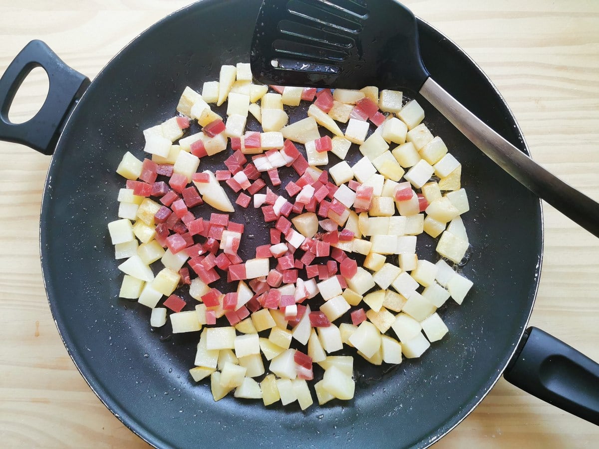 Cubed cooked potatoes and speck in large skillet.