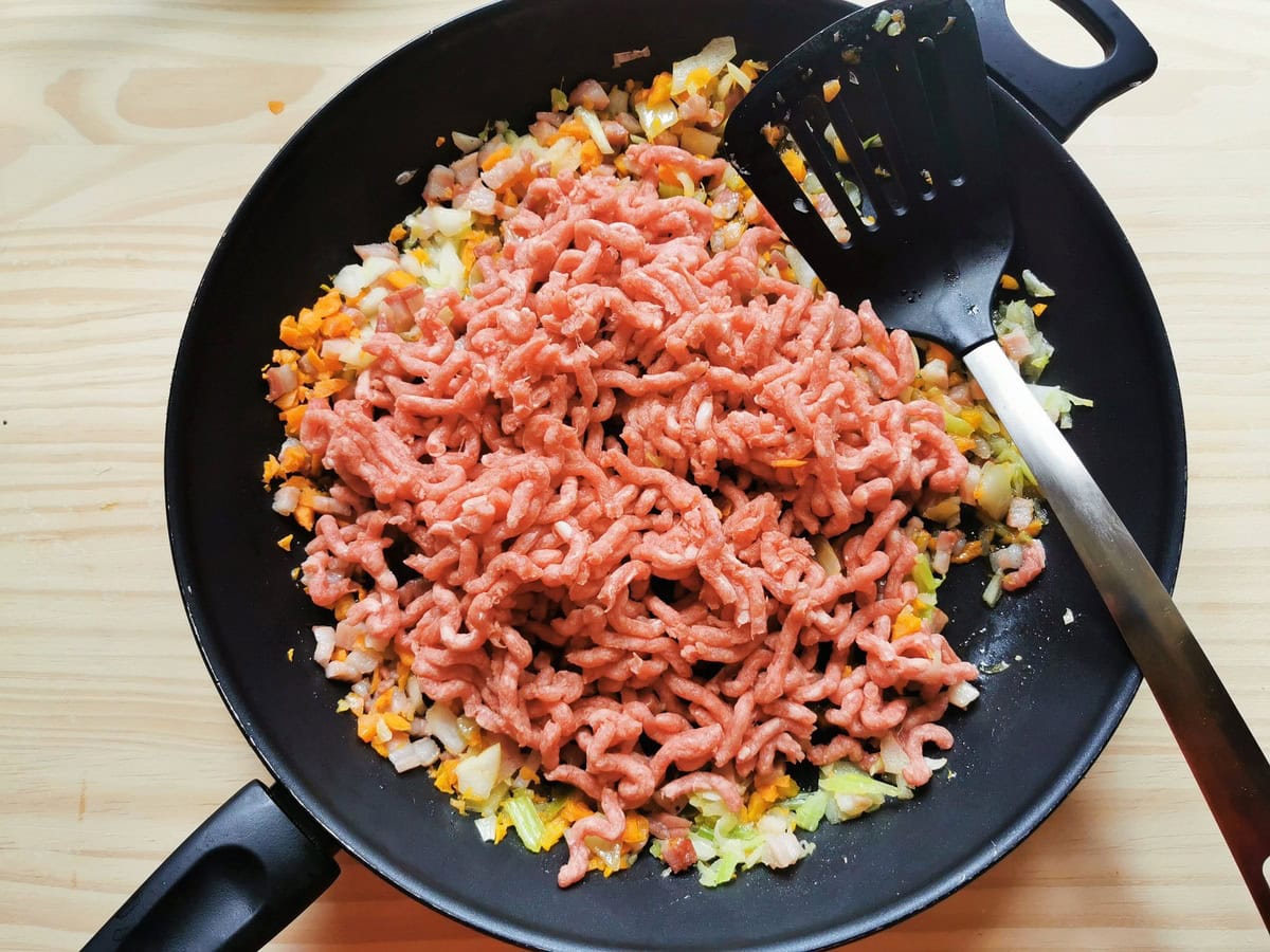 Raw ground beef added to skillet with the soffritto and pancetta.