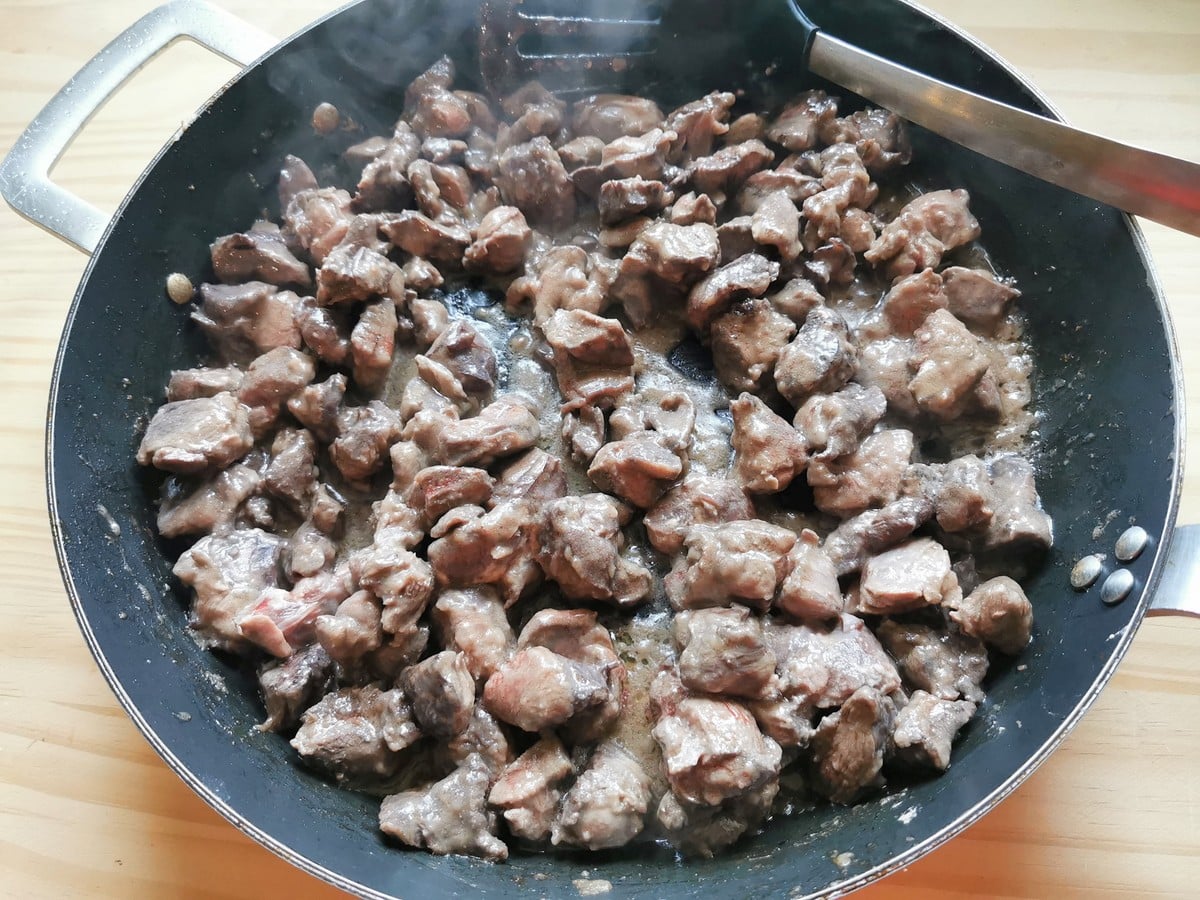 Cubes of hare meat cooking in skillet.