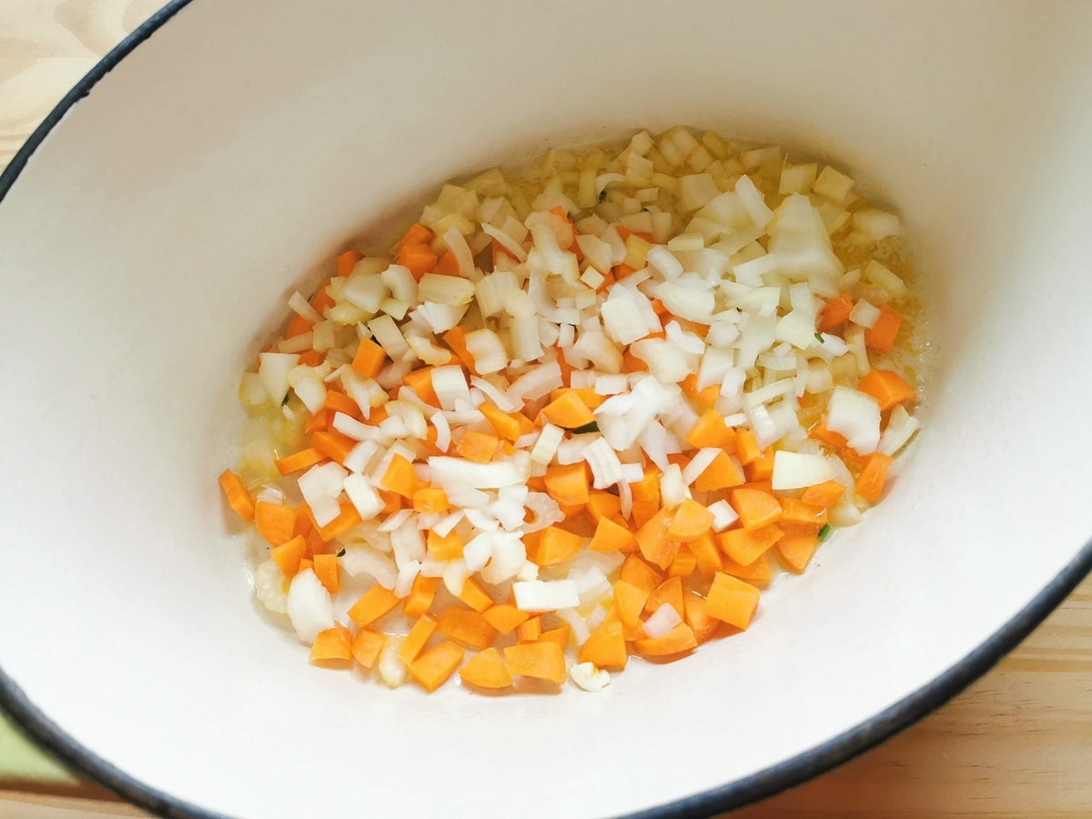 Prepared and chopped carrots, celery, onion and garlic cooking in Dutch oven.