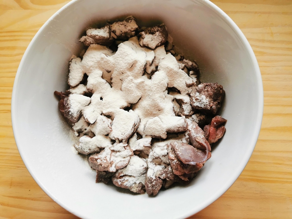 Hare meat pieces in white bowl with flour.