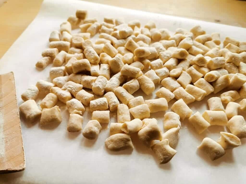 Ready uncooked breadcrumb gnocchi on floured tray.