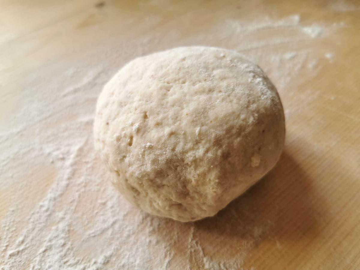 ready bread gnocchi dough rolled into a ball on pastry board.