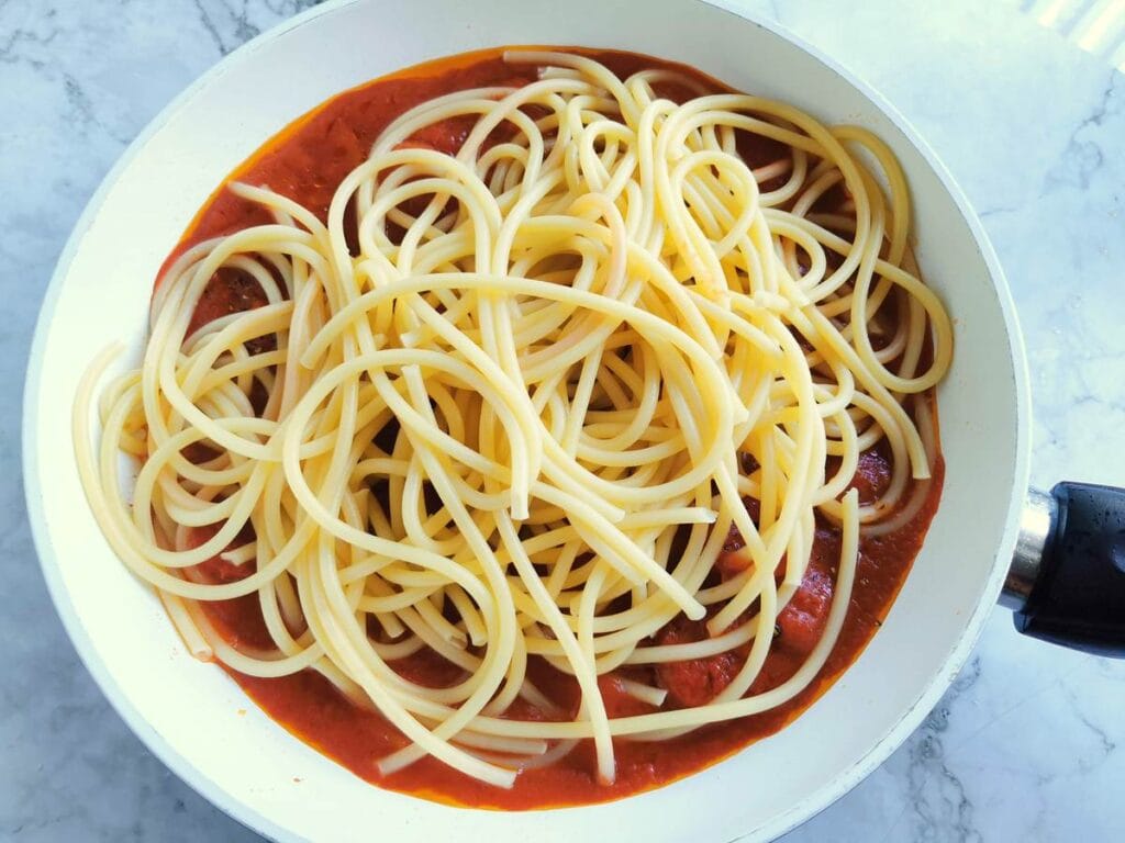 cooked bucatini in pan with arrabbiata sauce