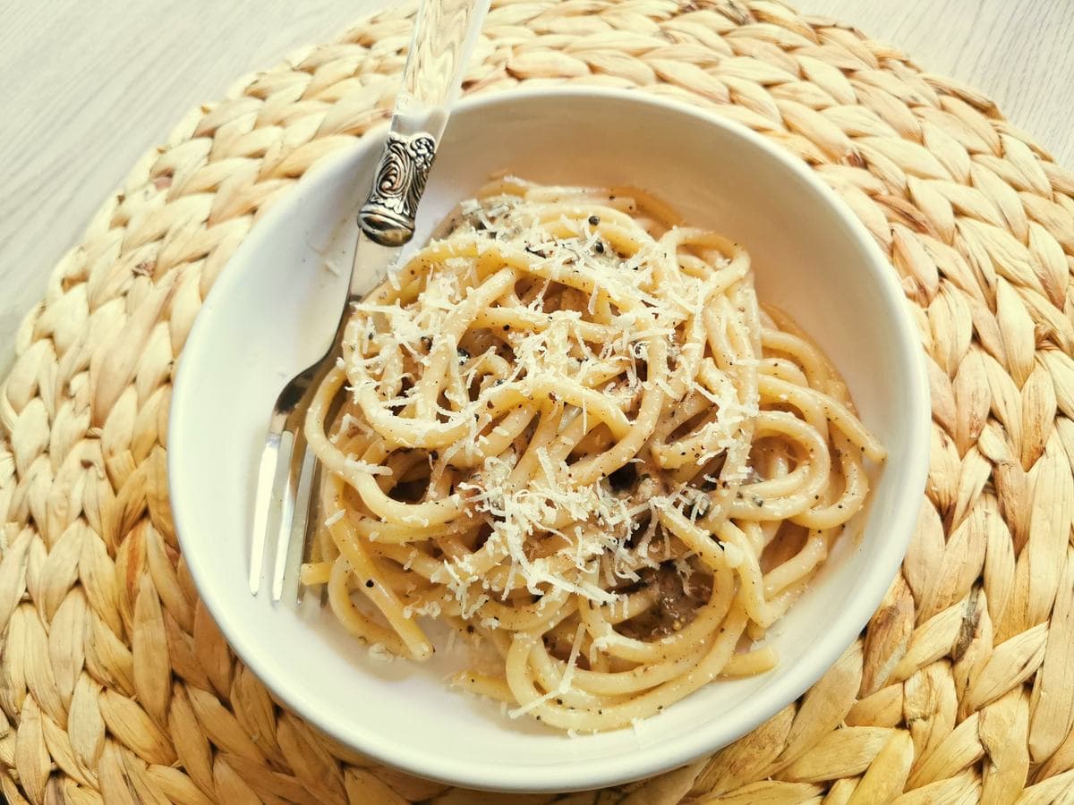 Pasta cacio e pepe garnished with cheese.