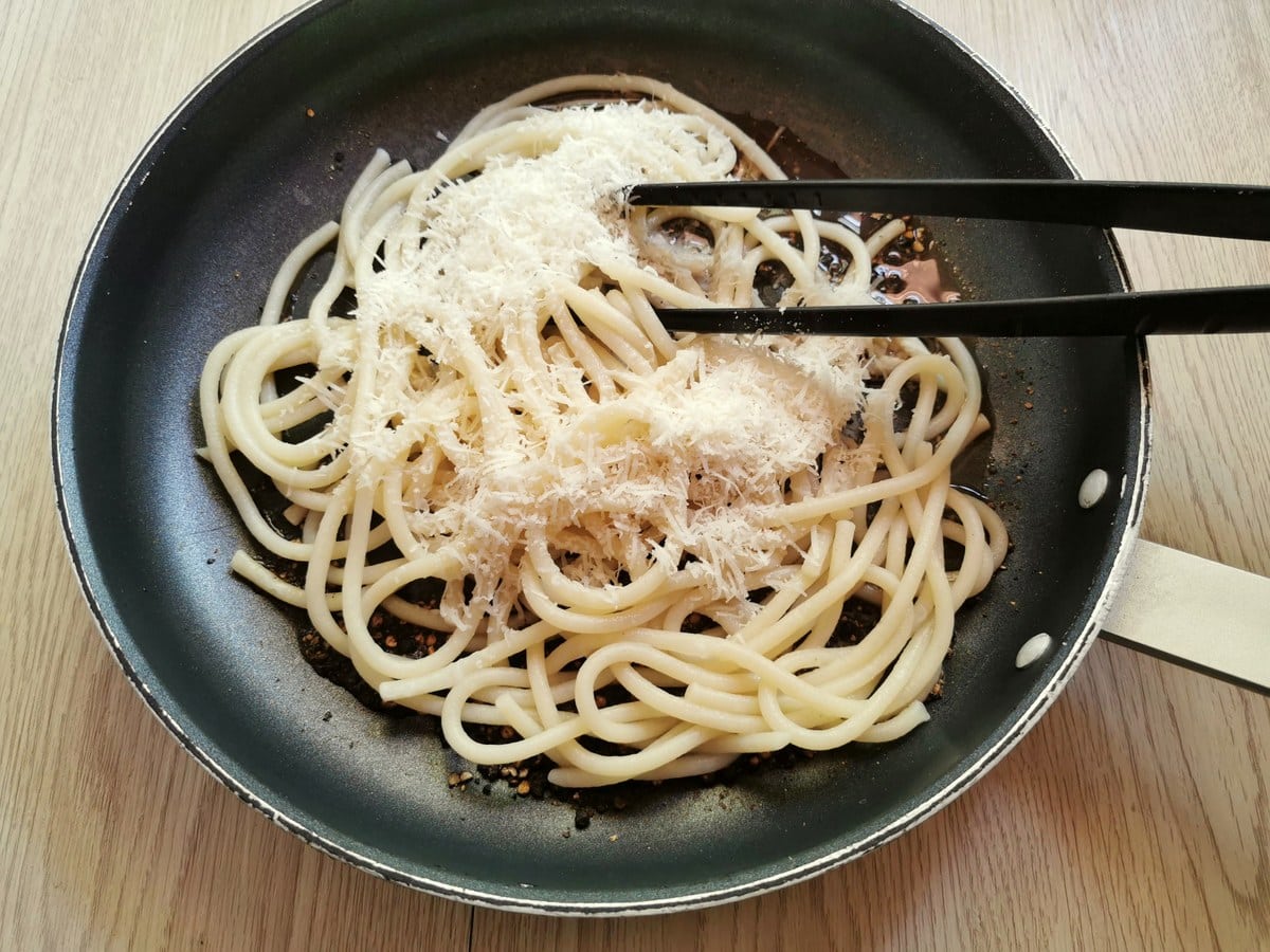 grated Pecorino Romano in pan with cooked thick spaghetti, pasta water and pepper.