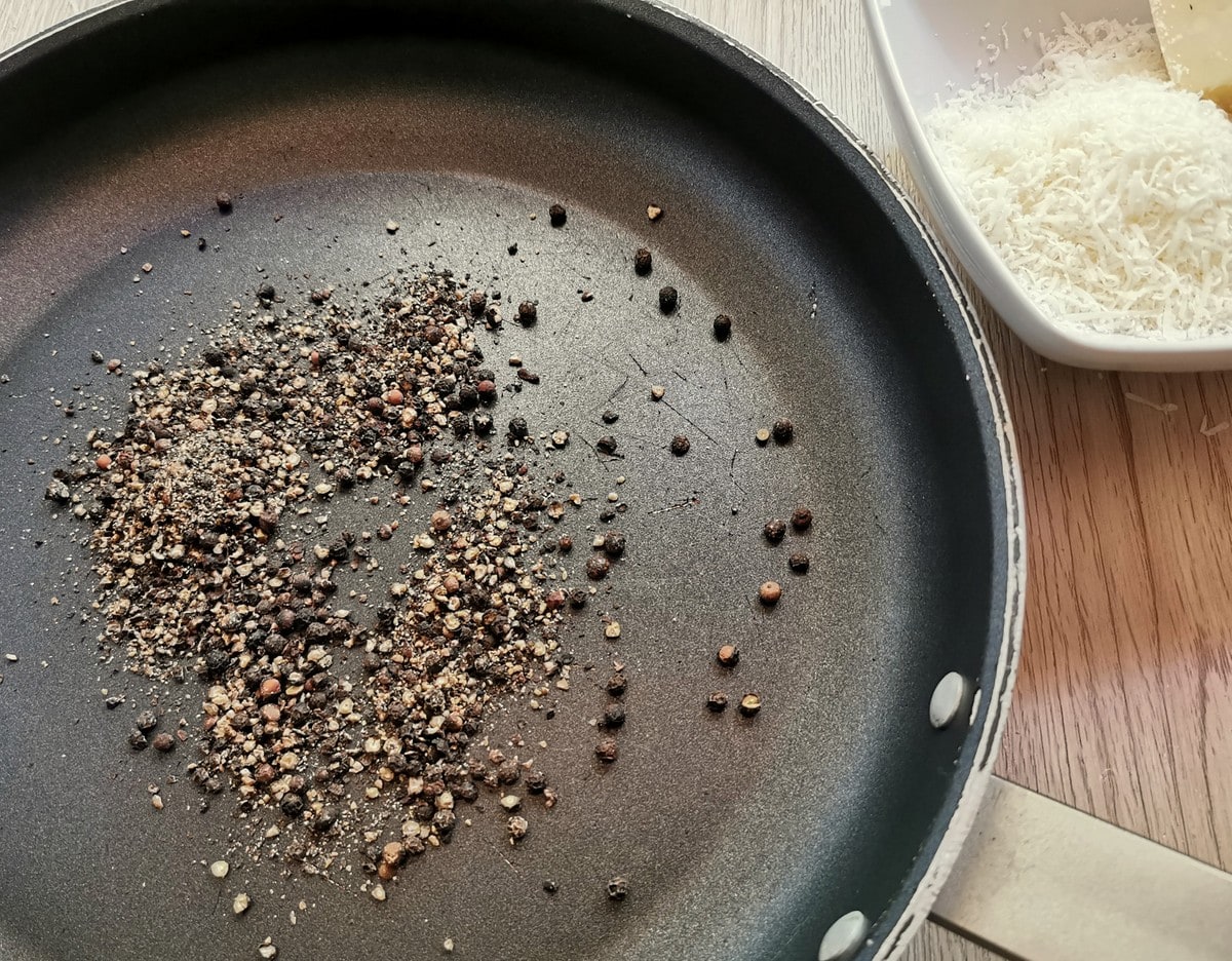 Crushed black pepper corns in a frying pan.