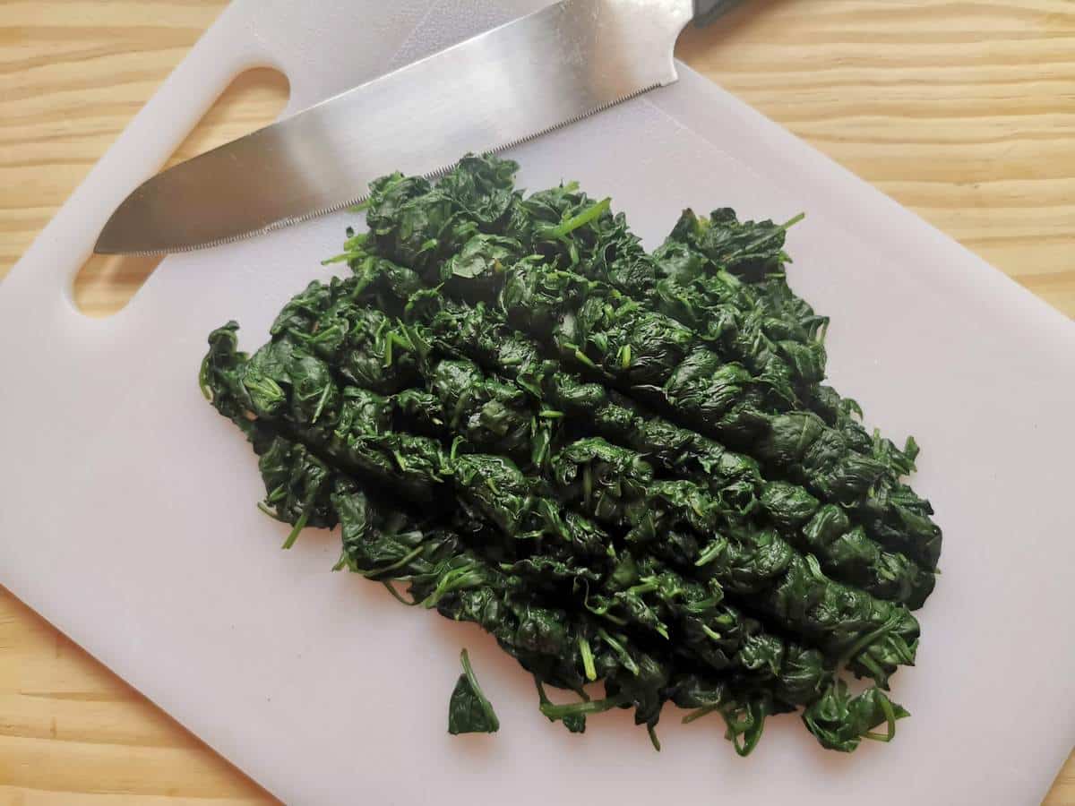 Wilted spinach chopped on a board.