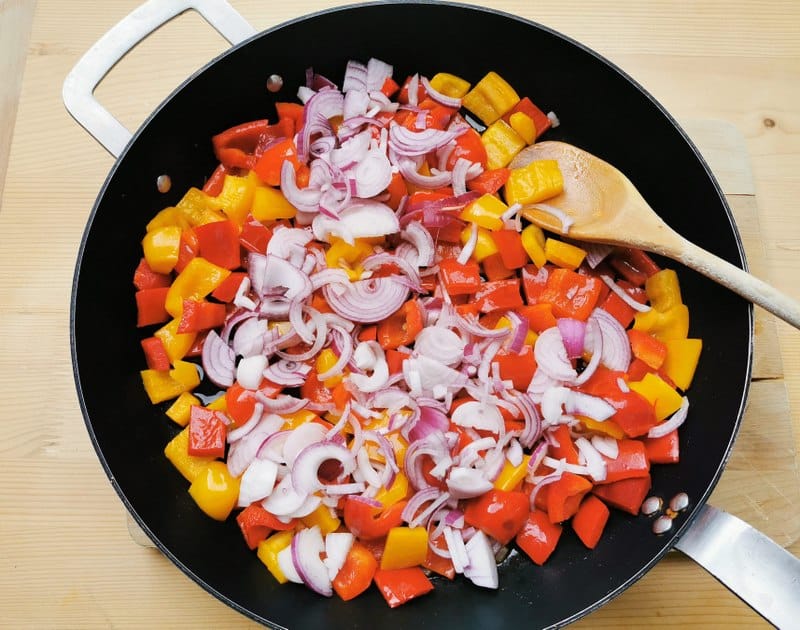 pieces of red and yellow peppers and chopped onion in skillet