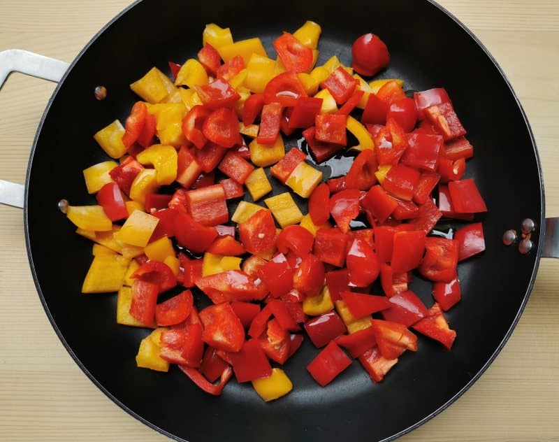 pieces of red and yellow peppers frying in skillet
