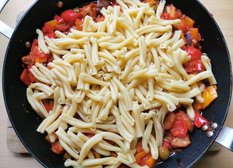 cooked casarecce pasta added to caponata in skillet