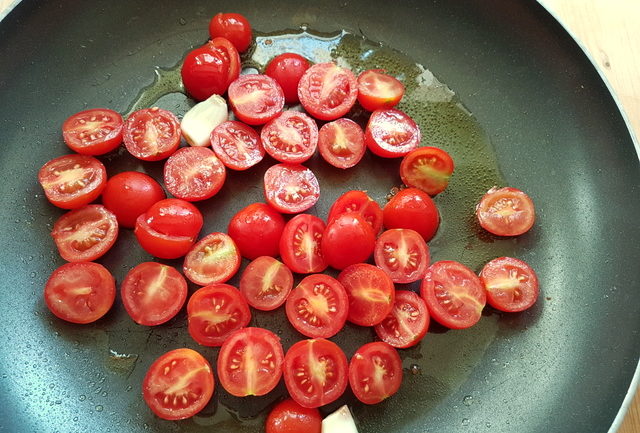 cherry tomatoes with olive oil and garlic in frying pan