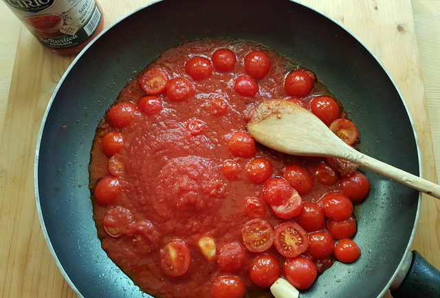 cherry tomatoes and tomato passata cooking in frying pan for tomato sauce