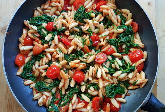 cavatelli pasta with rocket (arugula) in tomato sauce in frying pan