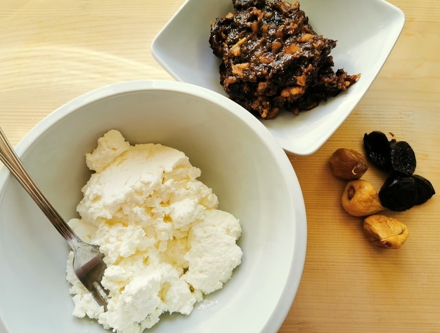 fresh ricotta in white bowl and chopped prunes and figs in white bowl