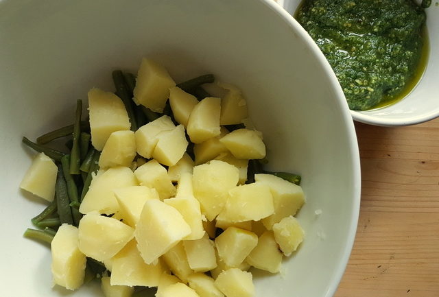 boiled potatoes and green beans in white bowl and homemade basil pesto in small white bowl