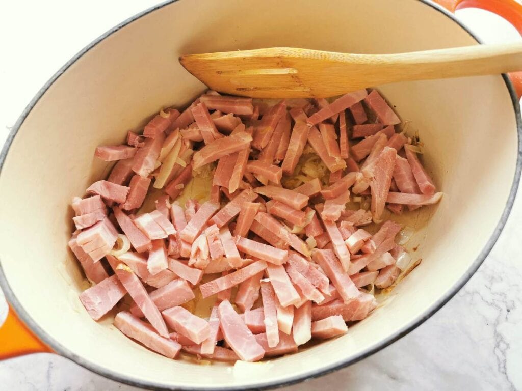 Pieces of ham in Dutch oven with shallots.