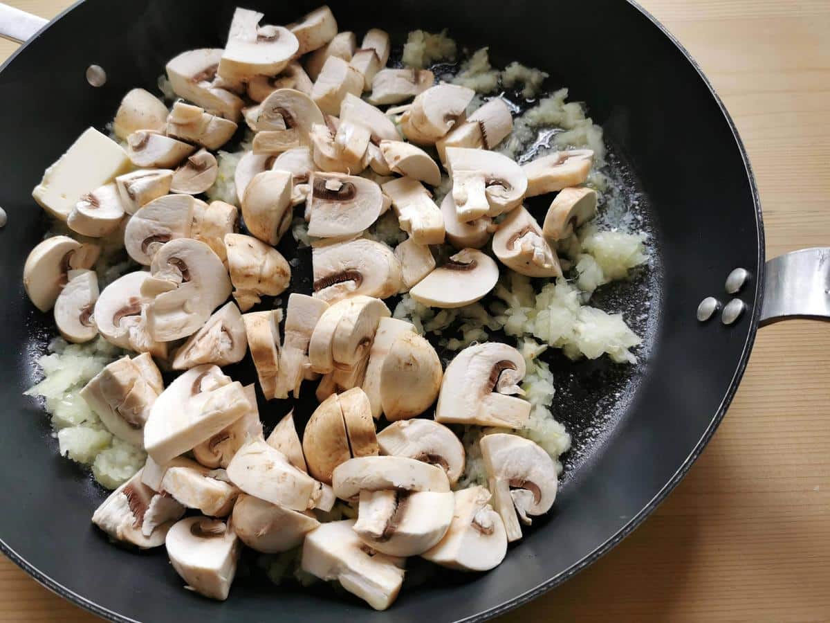 Mushrooms, onions, garlic and butter cooking in skillet.