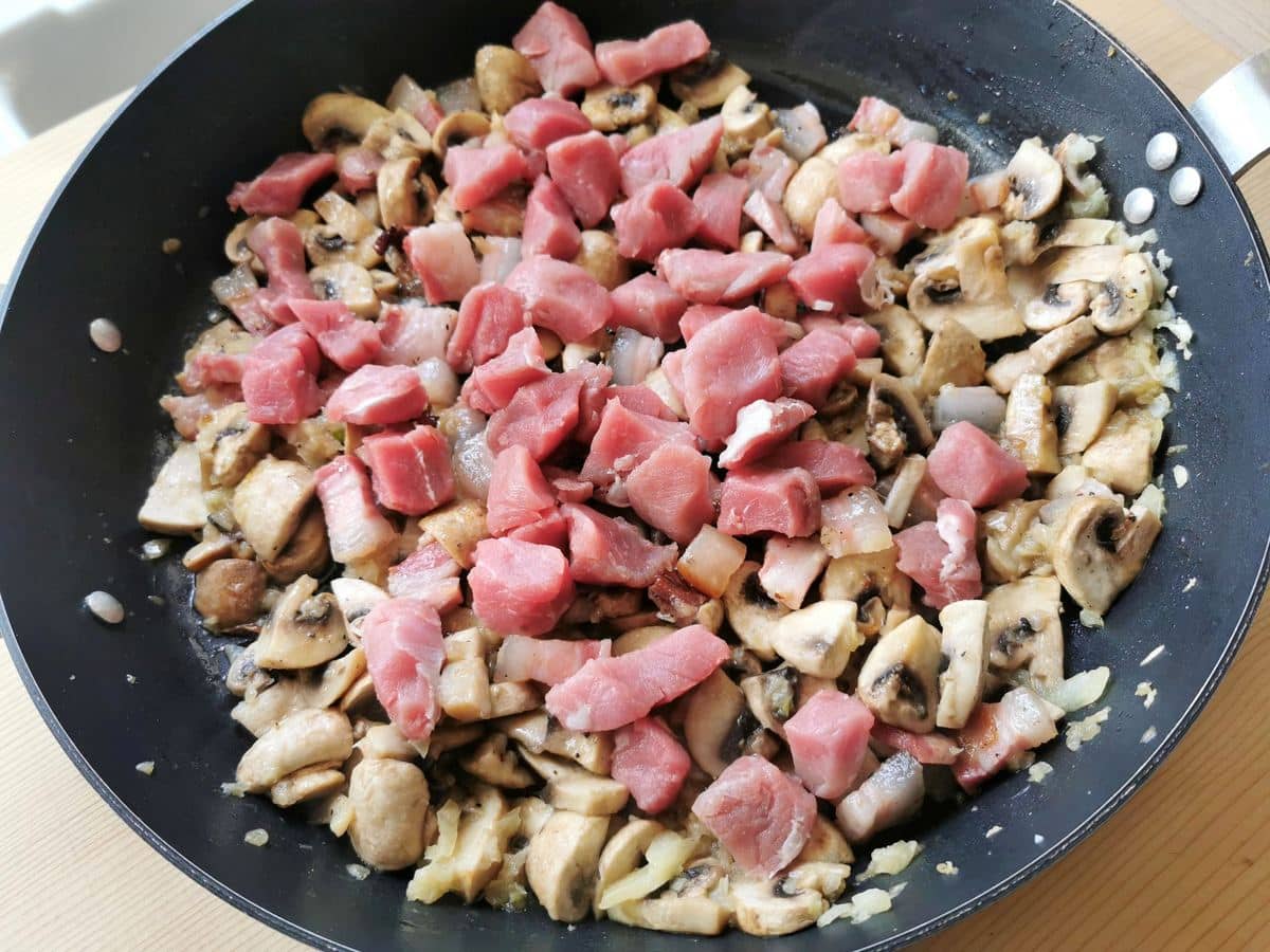 Chopped pork tenderloin (pork fillet) in skillet with other sauce ingredients.