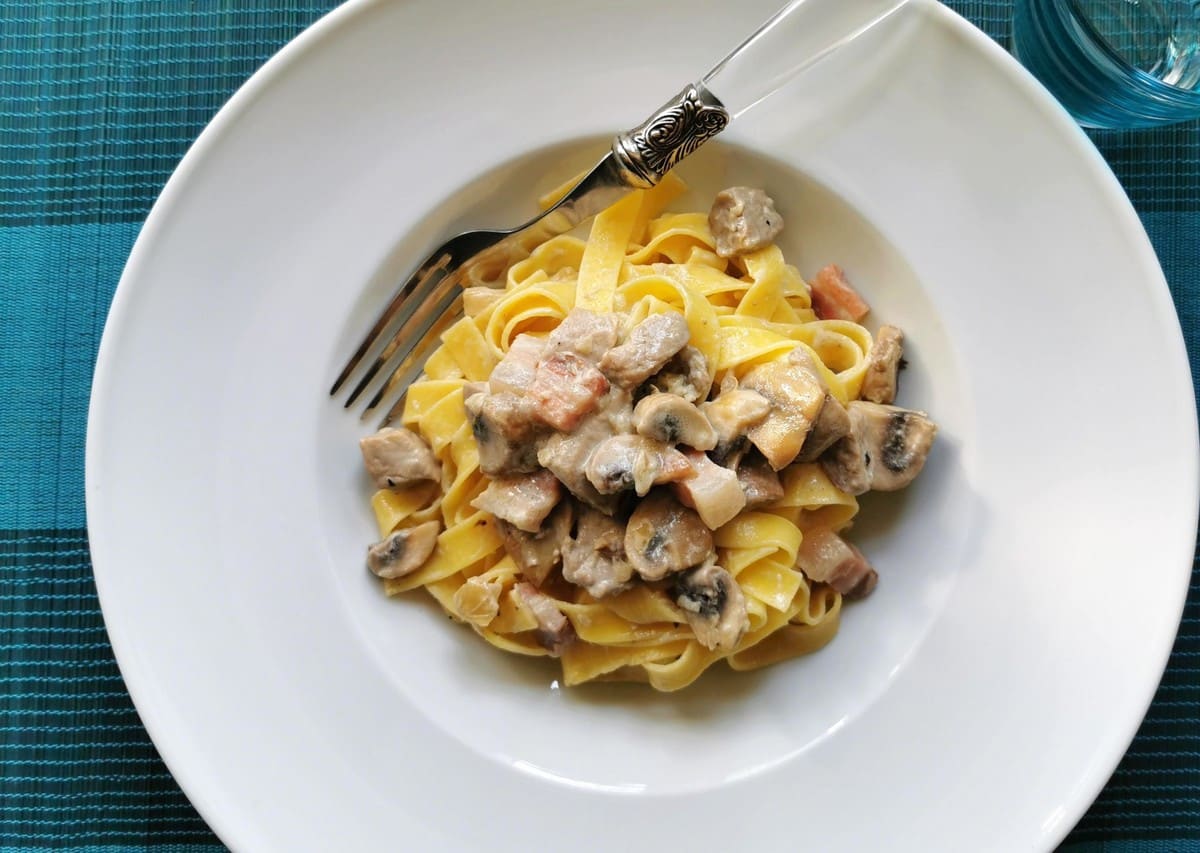 Creamy pork tenderloin pasta that has been plated on a kitchen table.