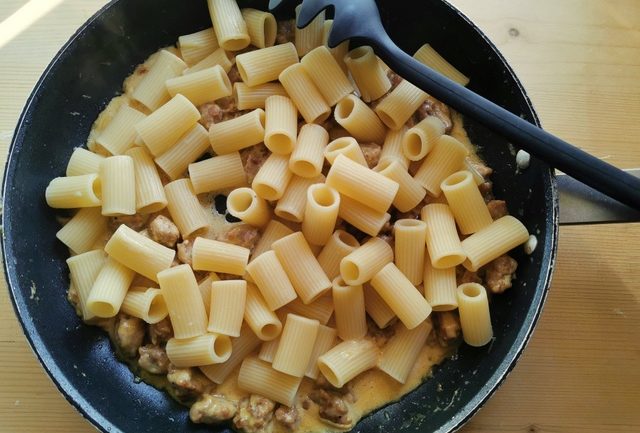 cooked rigatoni added to the sausage and saffron cream sauce in frying pan