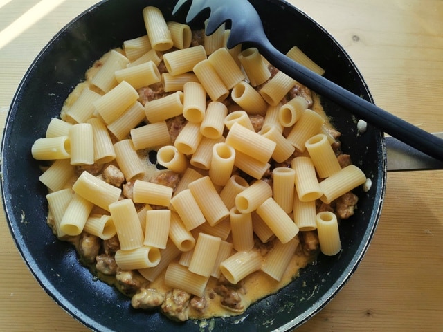 cooked rigatoni added to the sausage and saffron cream sauce in frying pan