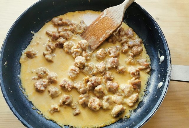 sausage, cream and saffron cooking in frying pan