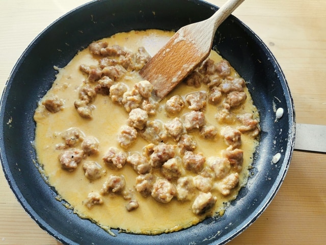 sausage, cream and saffron cooking in frying pan